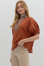 Rust Solid elasticated sleeve band dolman top featuring leopard print accented caftan-inspired split neck placket. Unlined. Woven. Non-sheer. Lightweight.