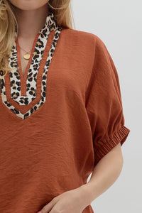 Rust Solid elasticated sleeve band dolman top featuring leopard print accented caftan-inspired split neck placket. Unlined. Woven. Non-sheer. Lightweight.