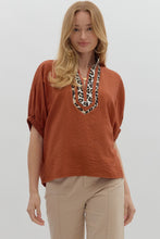 Rust Solid elasticated sleeve band dolman top featuring leopard print accented caftan-inspired split neck placket. Unlined. Woven. Non-sheer. Lightweight.
