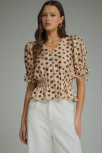 Polka dot V-neck short puff sleeve top featuring smocked waist. Button closure at front. Self-tie sleeve openings
