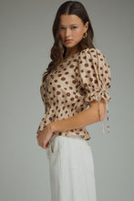 Polka dot V-neck short puff sleeve top featuring smocked waist. Button closure at front. Self-tie sleeve openings