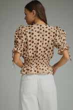 Polka dot V-neck short puff sleeve top featuring smocked waist. Button closure at front. Self-tie sleeve openings