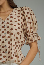 Polka dot V-neck short puff sleeve top featuring smocked waist. Button closure at front. Self-tie sleeve openings