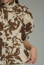 Brown Printed short puff sleeve top featuring button closure at front. Stand neck. Button cuffs. Unlined. Woven. Non-sheer. Lightweight.