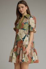Teal Floral short puff sleeve dress with a V-neck and contrast trim detail. Smocked cuffs. Side pockets. Ruffle hem. Lined. Woven. Non-sheer. Lightweight.