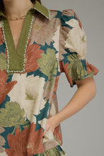 Teal Floral short puff sleeve dress with a V-neck and contrast trim detail. Smocked cuffs. Side pockets. Ruffle hem. Lined. Woven. Non-sheer. Lightweight.