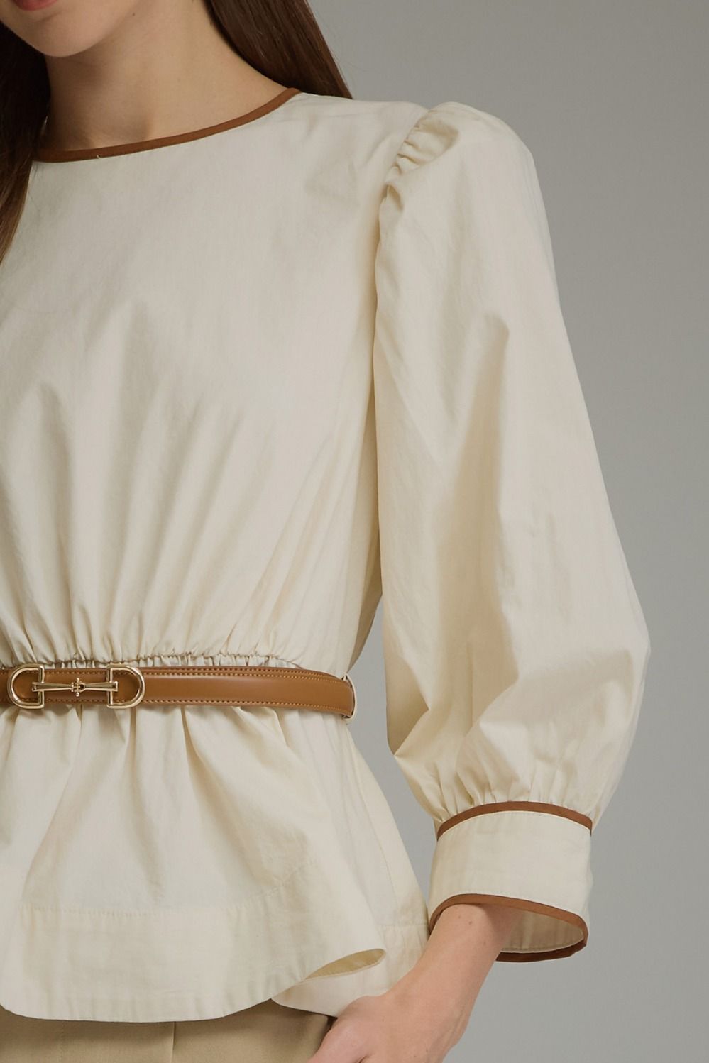 Solid long sleeve top with puff sleeves and contrast trim. Detachable belt included-ivory